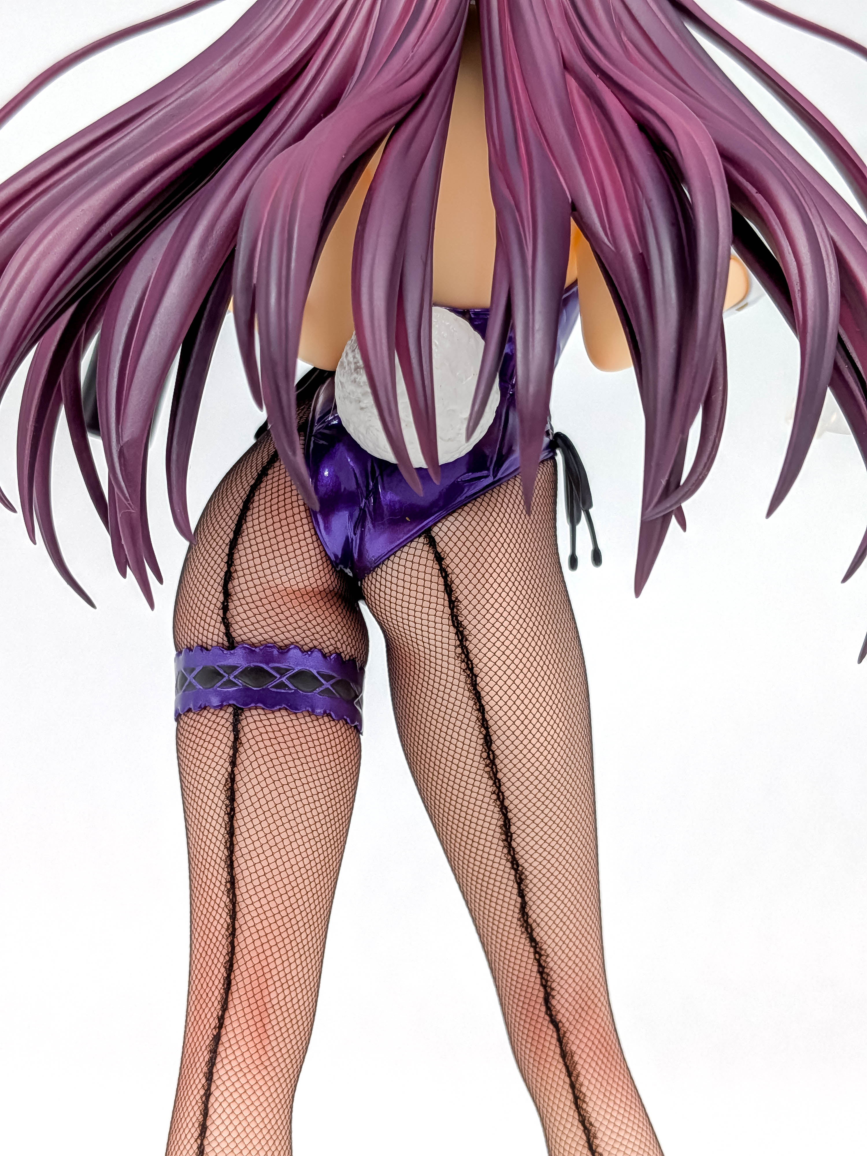 Rear close-up showing fishnet stockings, purple garter and white bunny tail